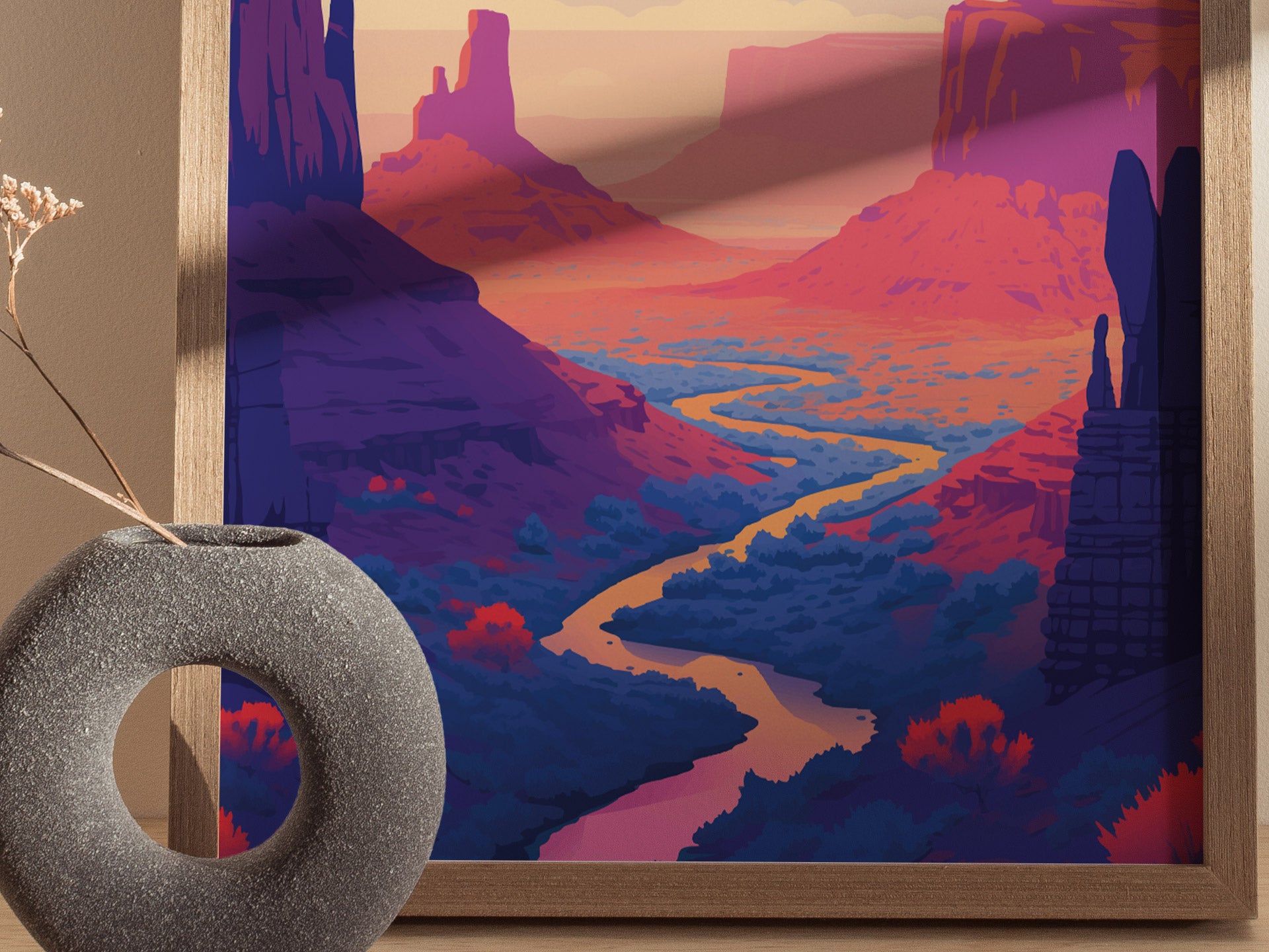 A vibrant poster features a winding river through a dramatic red rock desert landscape, with towering buttes under a colorful sky. A textured, round vase sits nearby.