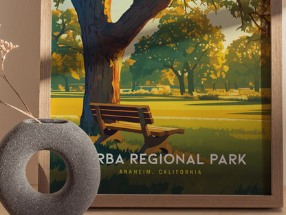 A framed poster of Yorba Regional Park features a sunlit landscape with a wooden bench under a large tree. A textured round vase with dried flowers is in the foreground.