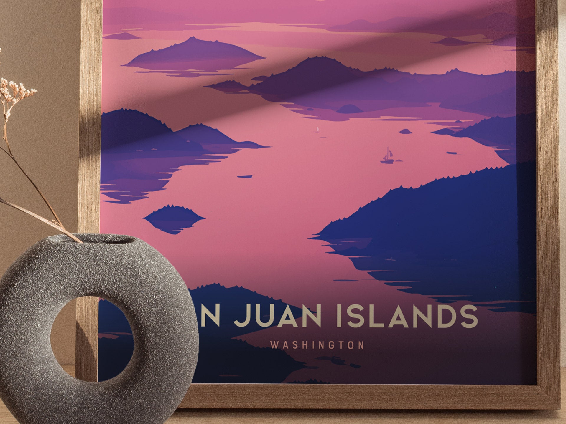 A framed poster of the San Juan Islands in Washington shows a pink and purple illustration of coastal waters and islands.