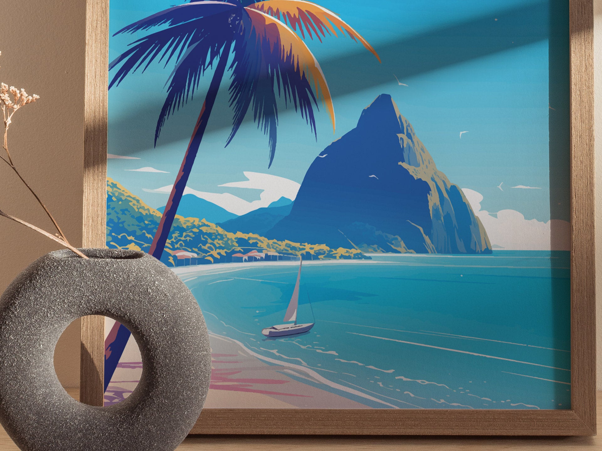 A framed artwork depicting a tropical beach scene with a sailboat, palm tree, and mountain against vibrant blue skies. A textured gray vase with dried flowers is in the foreground.