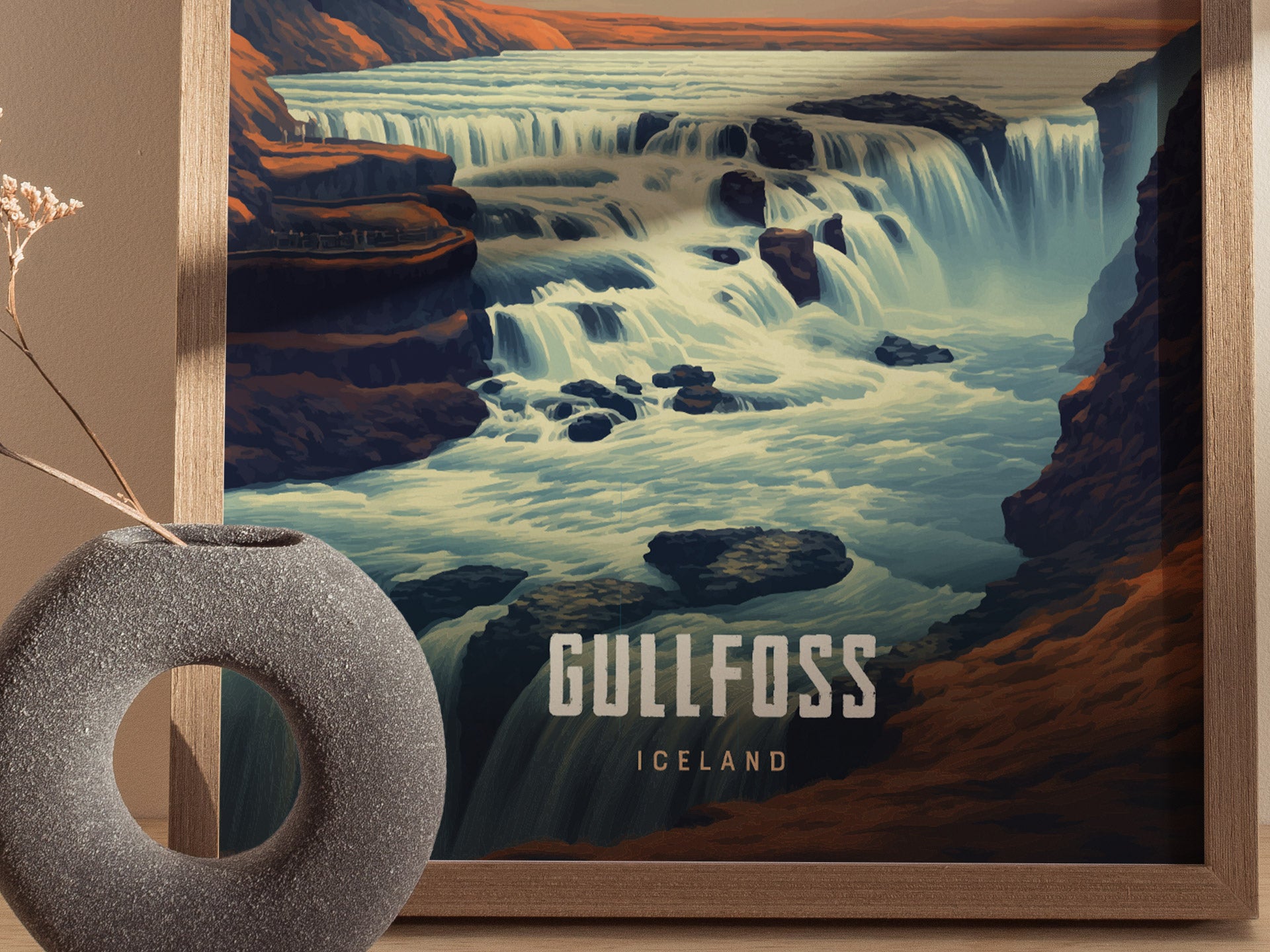 Framed artwork of Gullfoss waterfall in Iceland, showcasing cascading water in a dramatic landscape. A textured, circular vase with dried flowers is placed in the foreground.