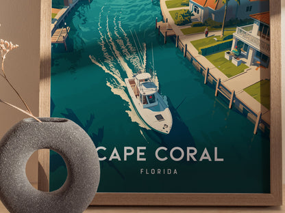 A framed poster features a vibrant illustration of a boat navigating a canal lined with tropical homes in Cape Coral, Florida. A decorative vase is visible in the foreground.