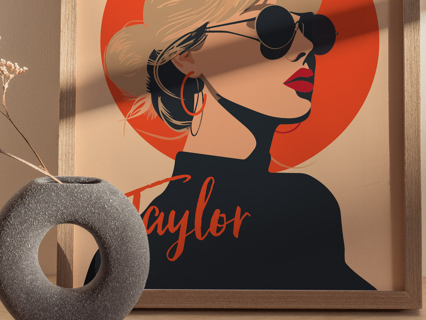 A framed minimal art poster features a stylized illustration of a woman in sunglasses against a bright orange circle, with a textured vase nearby.