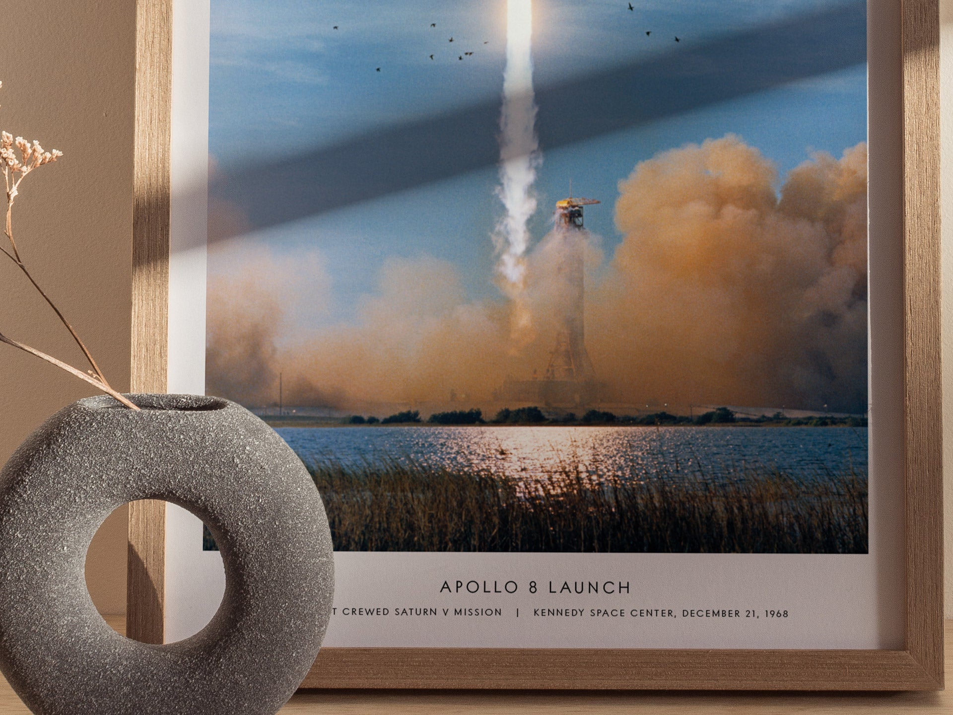 Framed print of Apollo 8 launch with decorative vase on a table