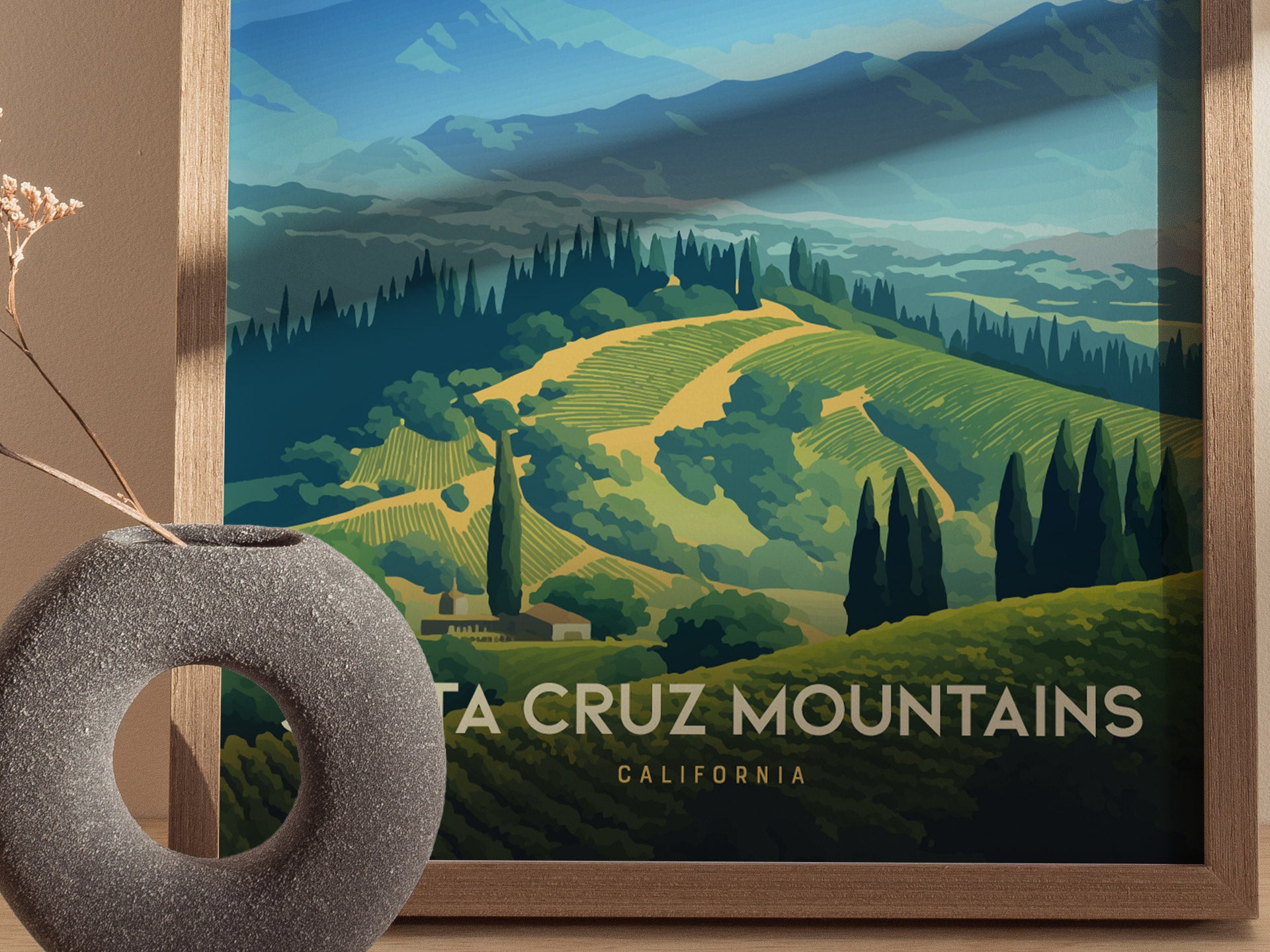 A poster depicting the Santa Cruz Mountains with vibrant green vineyards and tall cypress trees under blue mountain peaks, framed in wood.