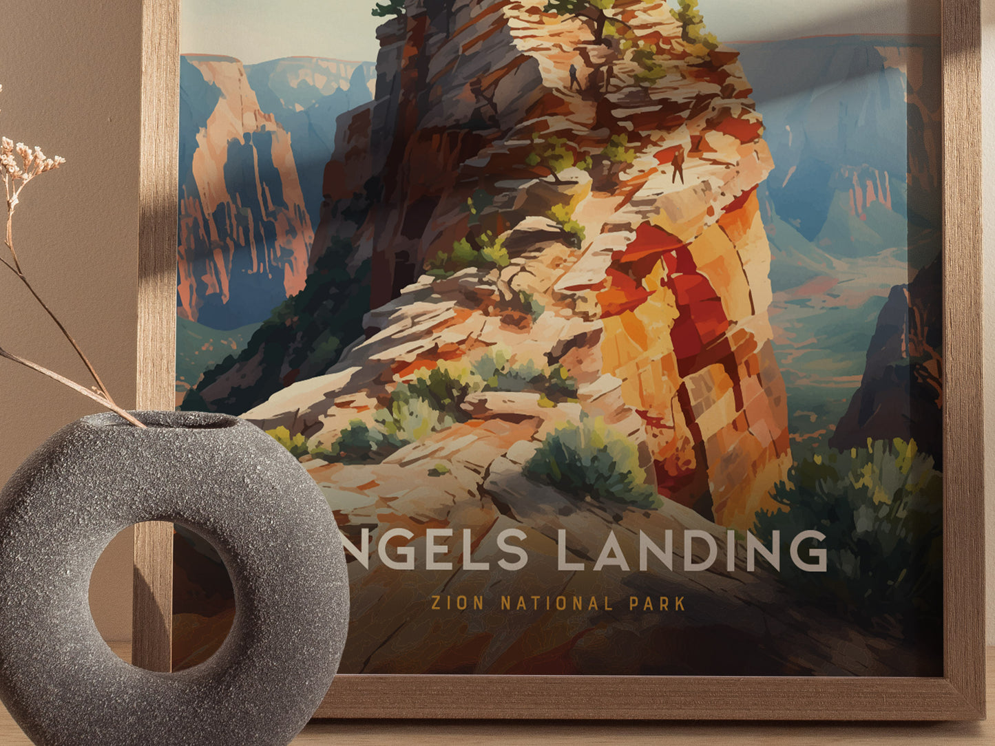 A framed poster of Angels Landing in Zion National Park is displayed, featuring a colorful sandstone ridge with lush greenery. A round, textured vase is placed in the foreground.