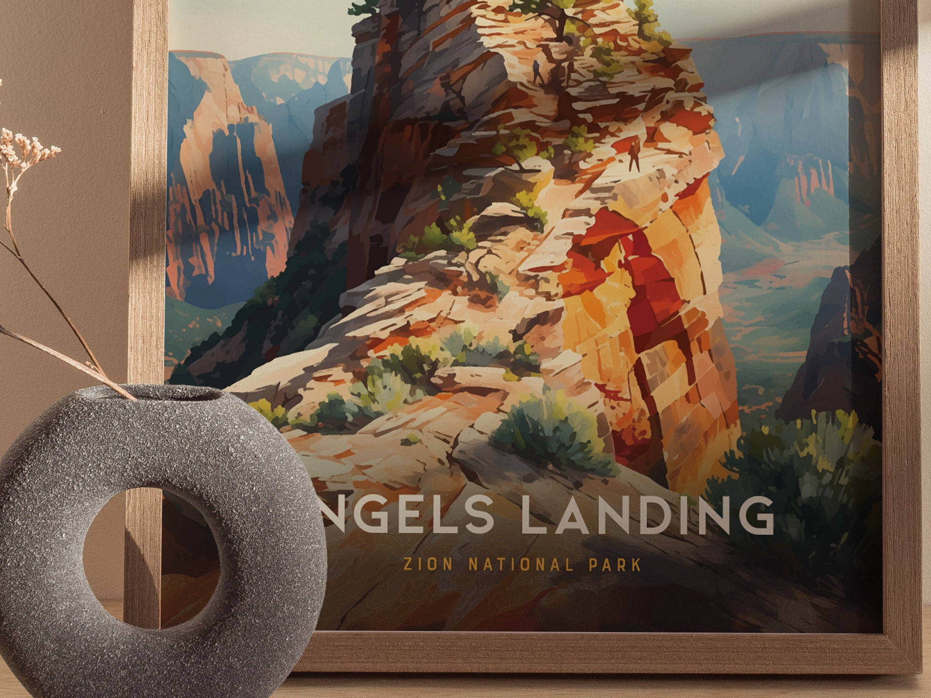 A framed poster of Angels Landing in Zion National Park is displayed, featuring a colorful sandstone ridge with lush greenery. A round, textured vase is placed in the foreground.