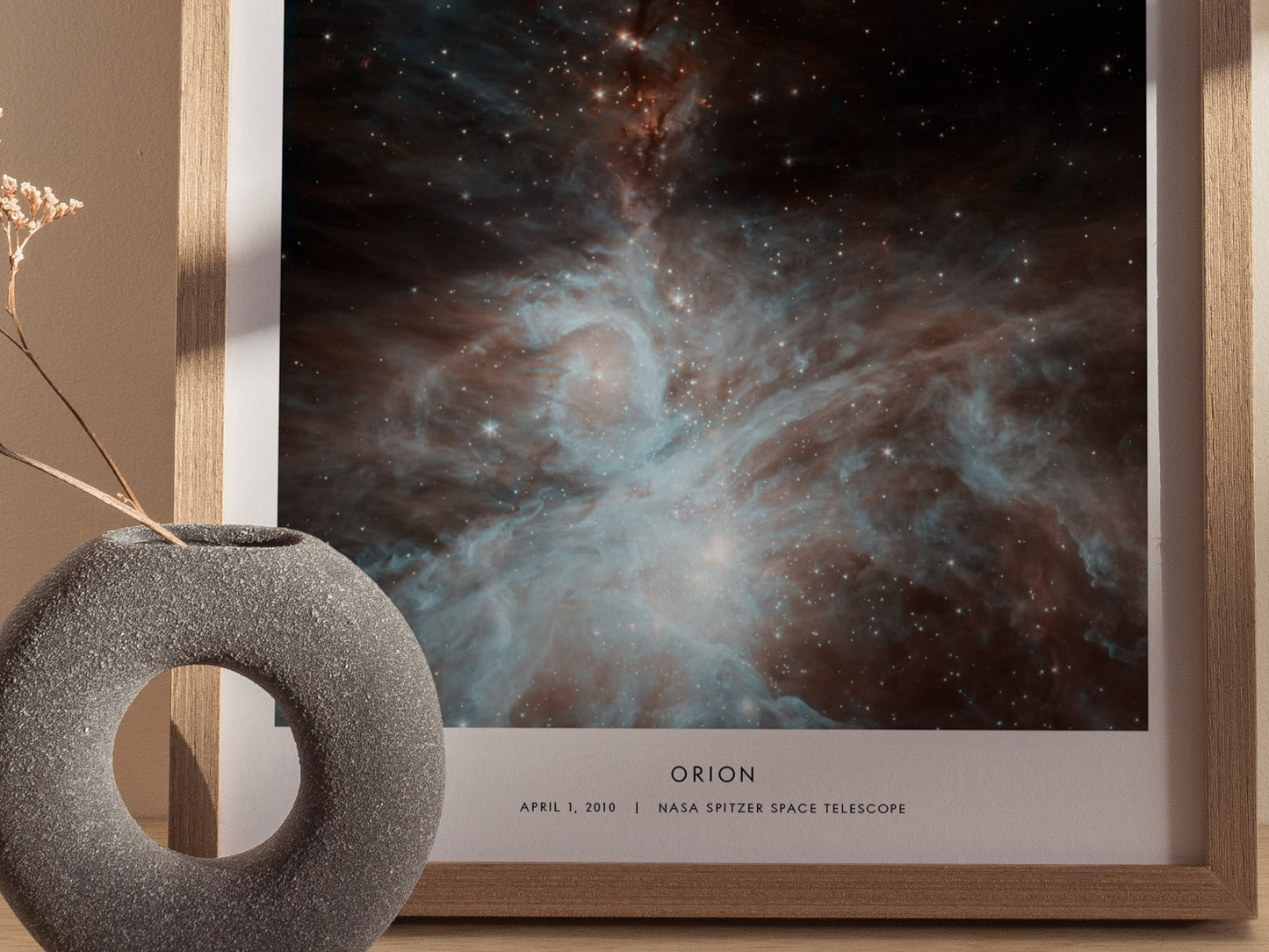 Framed photograph of the Orion nebula with a decorative object on a beige surface