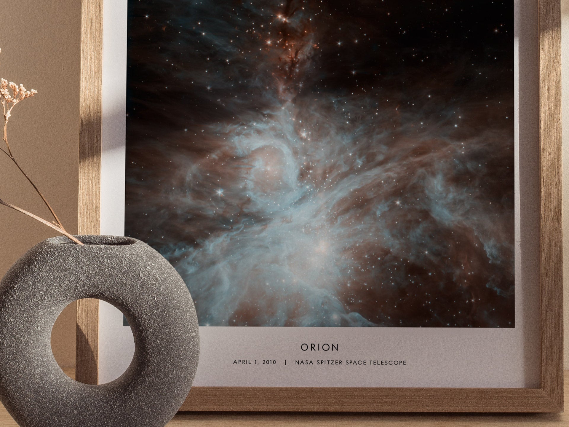 Framed photograph of the Orion nebula with a decorative object on a beige surface