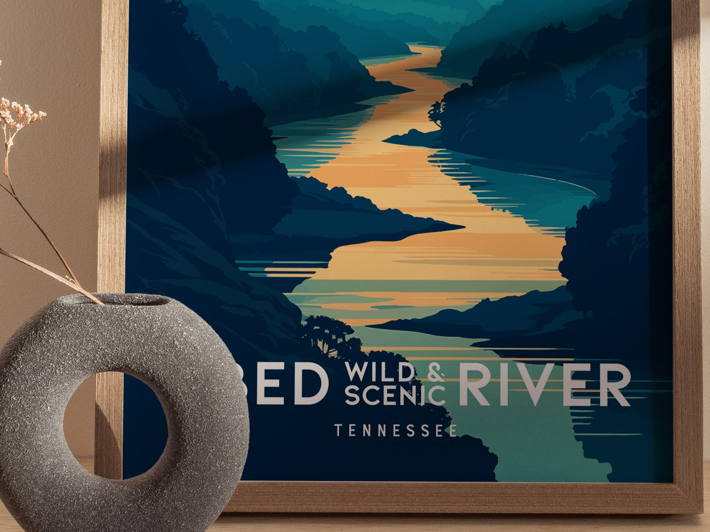 A framed poster of Obed Wild and Scenic River features a stylized river landscape in blue and green tones, with bold text. A round, textured vase sits nearby.