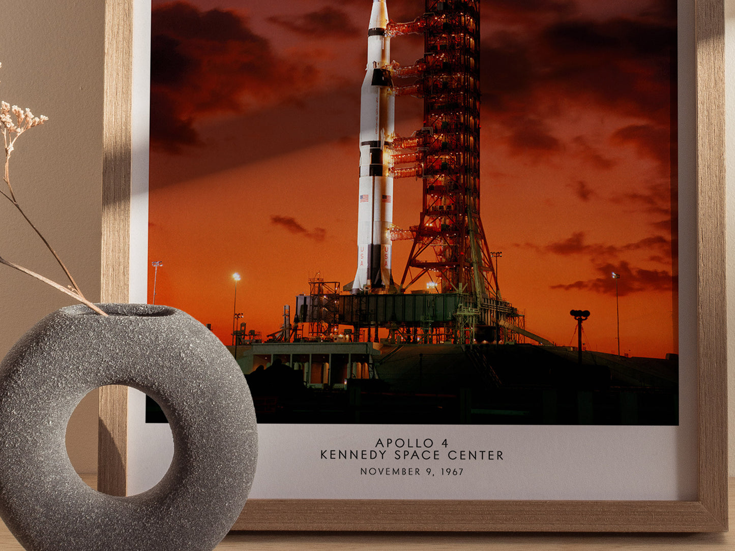 Framed photograph of Apollo 4 launch at Kennedy Space Center with decorative object in foreground.