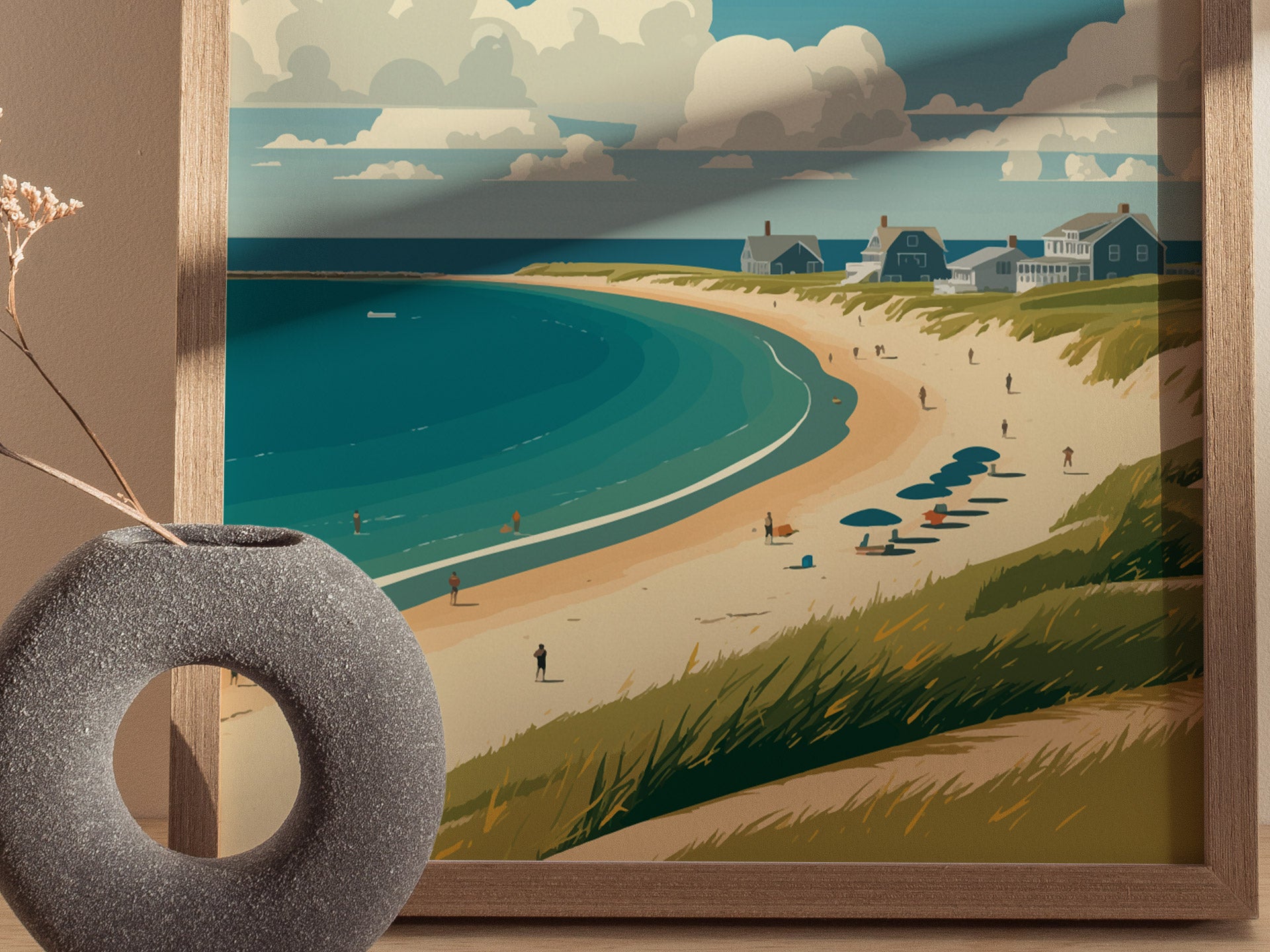 A framed coastal artwork depicts a sandy beach with umbrellas and distant cottages under a cloudy sky. A textured stone vase with dried flowers sits in the foreground.