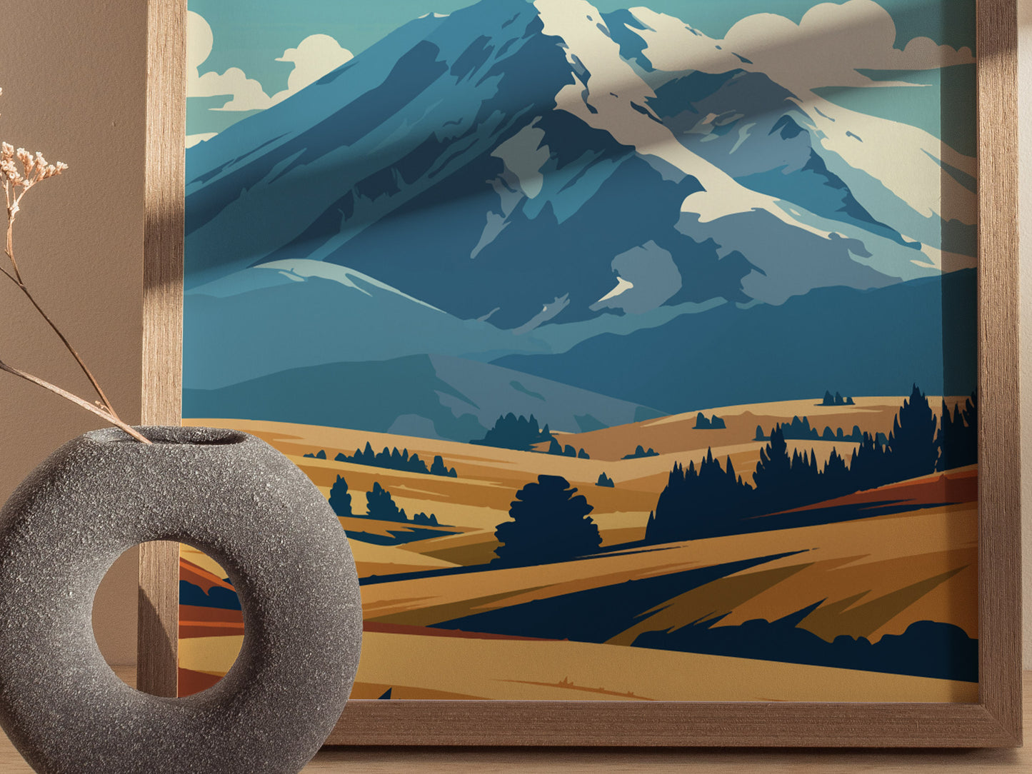 A framed poster depicting a stylized mountain landscape with blue peaks and golden fields, accompanied by a modern stone vase holding dried flowers in the foreground.