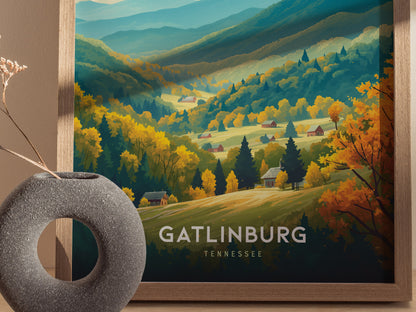 A vibrant poster of Gatlinburg, Tennessee, features lush, colorful mountains and valleys with scattered houses, framed in wood. A round, textured vase sits in the foreground.
