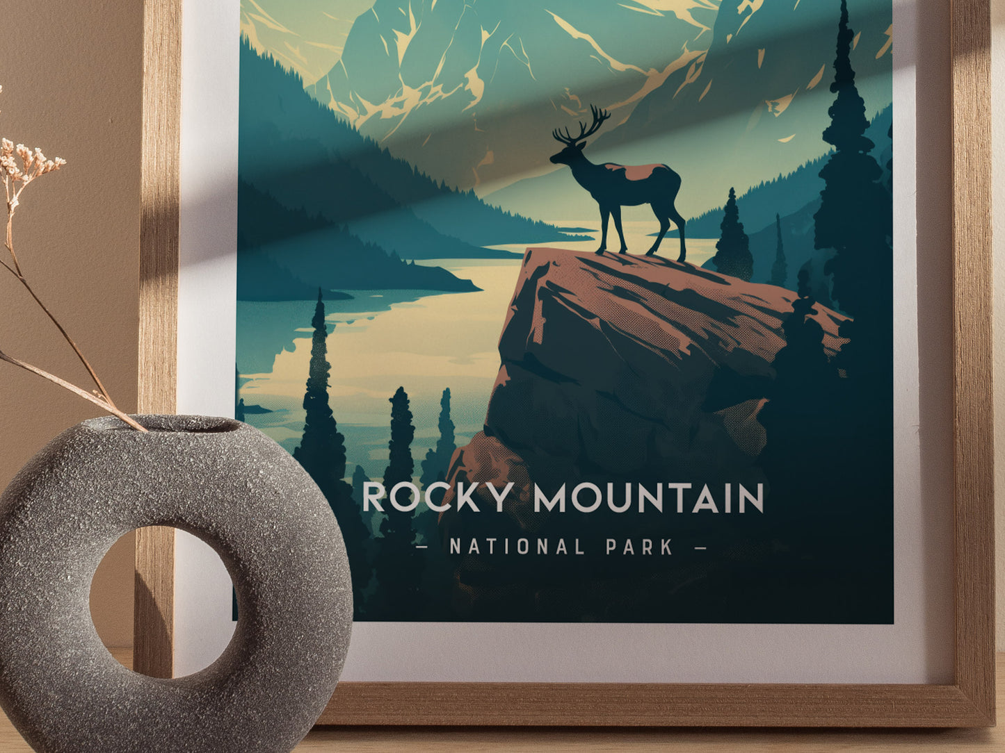 A minimalist poster of Rocky Mountain National Park shows a lone elk on a cliff, with mountains and a lake in the background.
