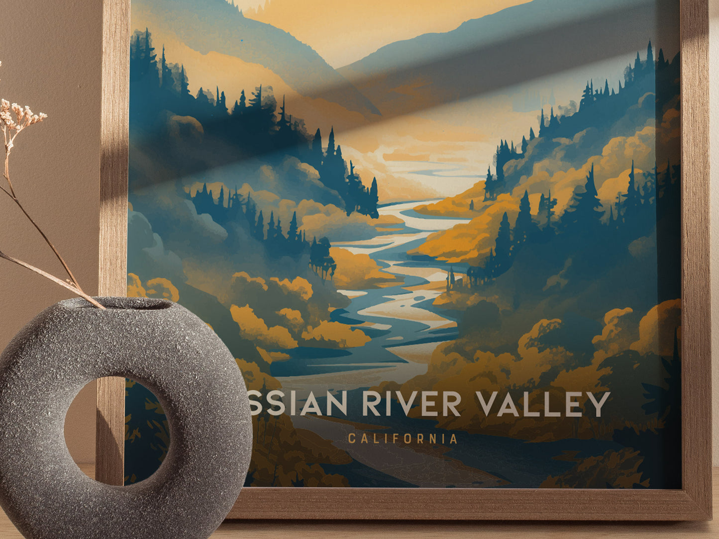 A framed poster depicts a stylized landscape of the Russian River Valley with vibrant blue and gold hues, surrounded by hills and trees. A round, textured vase sits nearby.