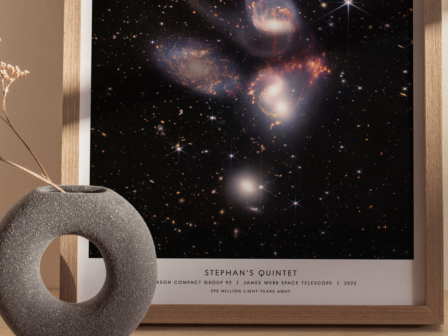 Framed poster of Stephan's Quintet galaxy with a decorative stone object on a neutral background