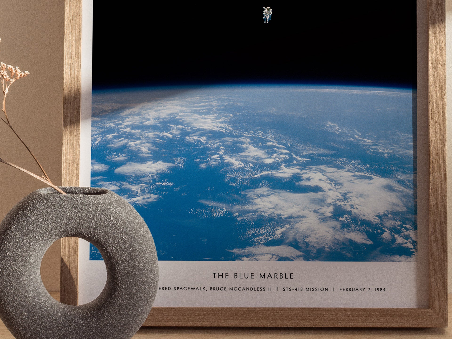 Framed print of 'The Blue Marble' with Earth view and space shuttle, placed on a surface.