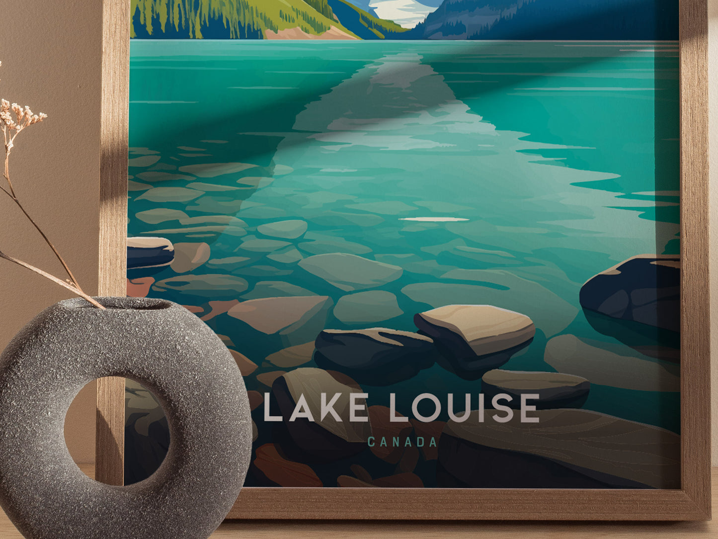 A framed Lake Louise poster features turquoise water and rocky shores, with the words Lake Louise, Canada visible. A textured gray vase with dried flowers is in the foreground.