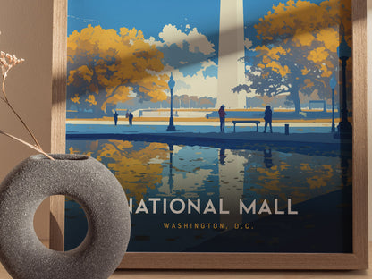 A framed poster depicting the Washington D.C. National Mall with autumn trees, silhouetted figures, and a reflective water scene. A round stone vase with dried flowers is in the foreground.
