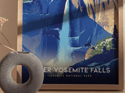 A framed poster of Upper Yosemite Falls features a stylized depiction of the waterfall with blue and orange hues, next to a round, textured vase with dried flowers.