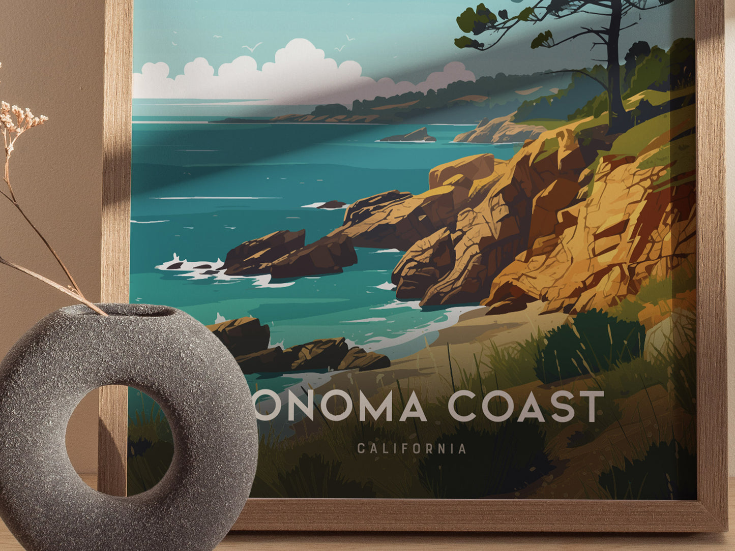 A framed poster depicting a stylized Sonoma Coast scene with rocky cliffs, ocean waves, and vibrant greenery. A round, textured vase with dried flowers is in the foreground.