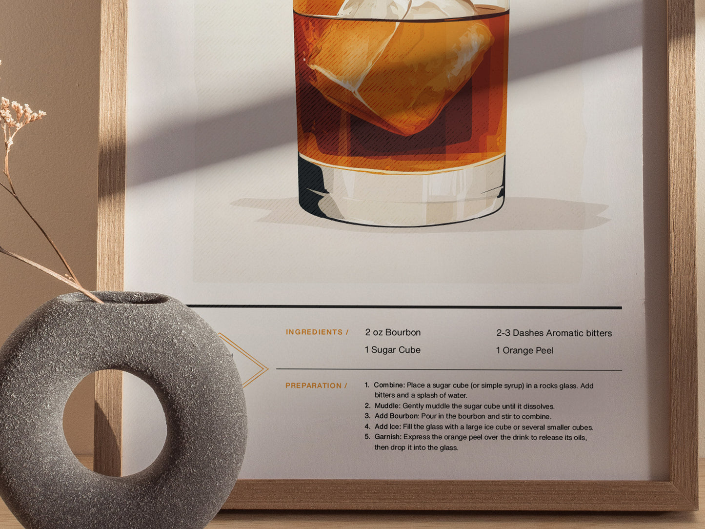A framed poster features an illustration of an Old Fashioned cocktail with visible ingredients and preparation steps. A textured circular vase with dried flowers is in the foreground.