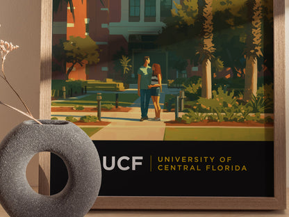 A framed poster of the University of Central Florida campus features two people walking among palm trees. The foreground includes a modern vase with dried flowers.
