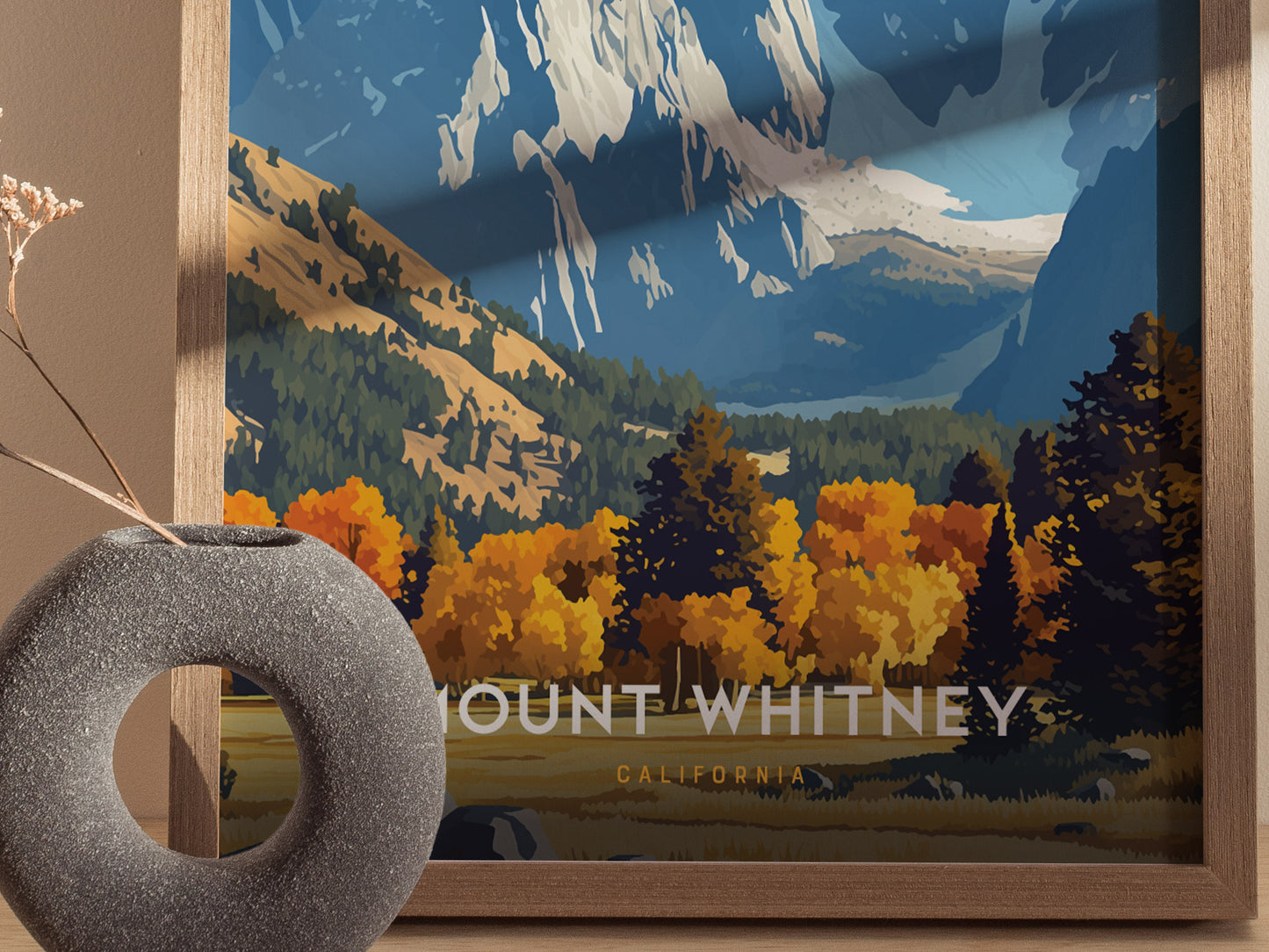 A framed poster of Mount Whitney featuring vibrant autumn foliage and rugged mountain peaks, with a round, gray vase in the foreground. The text reads Mount Whitney California.