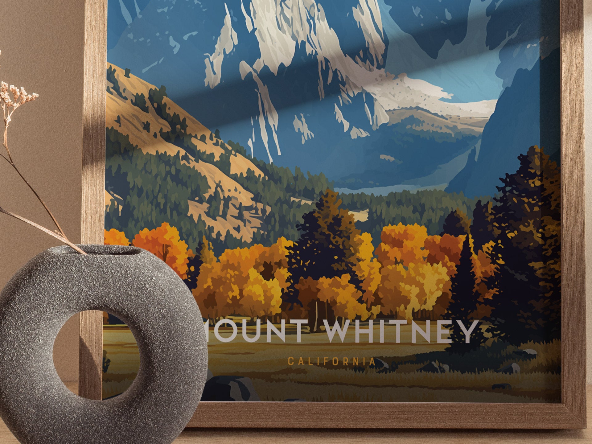 A framed poster of Mount Whitney featuring vibrant autumn foliage and rugged mountain peaks, with a round, gray vase in the foreground. The text reads Mount Whitney California.