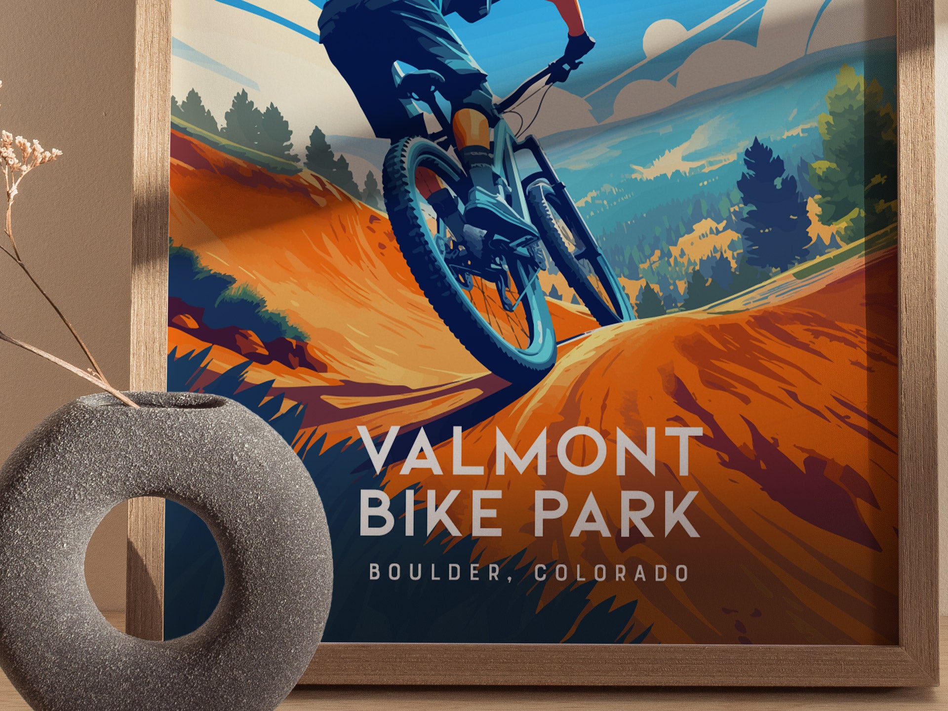 A vibrant poster depicts a mountain biker on an orange trail with lush green trees and mountains in the background, labeled Valmont Bike Park, Boulder, Colorado.