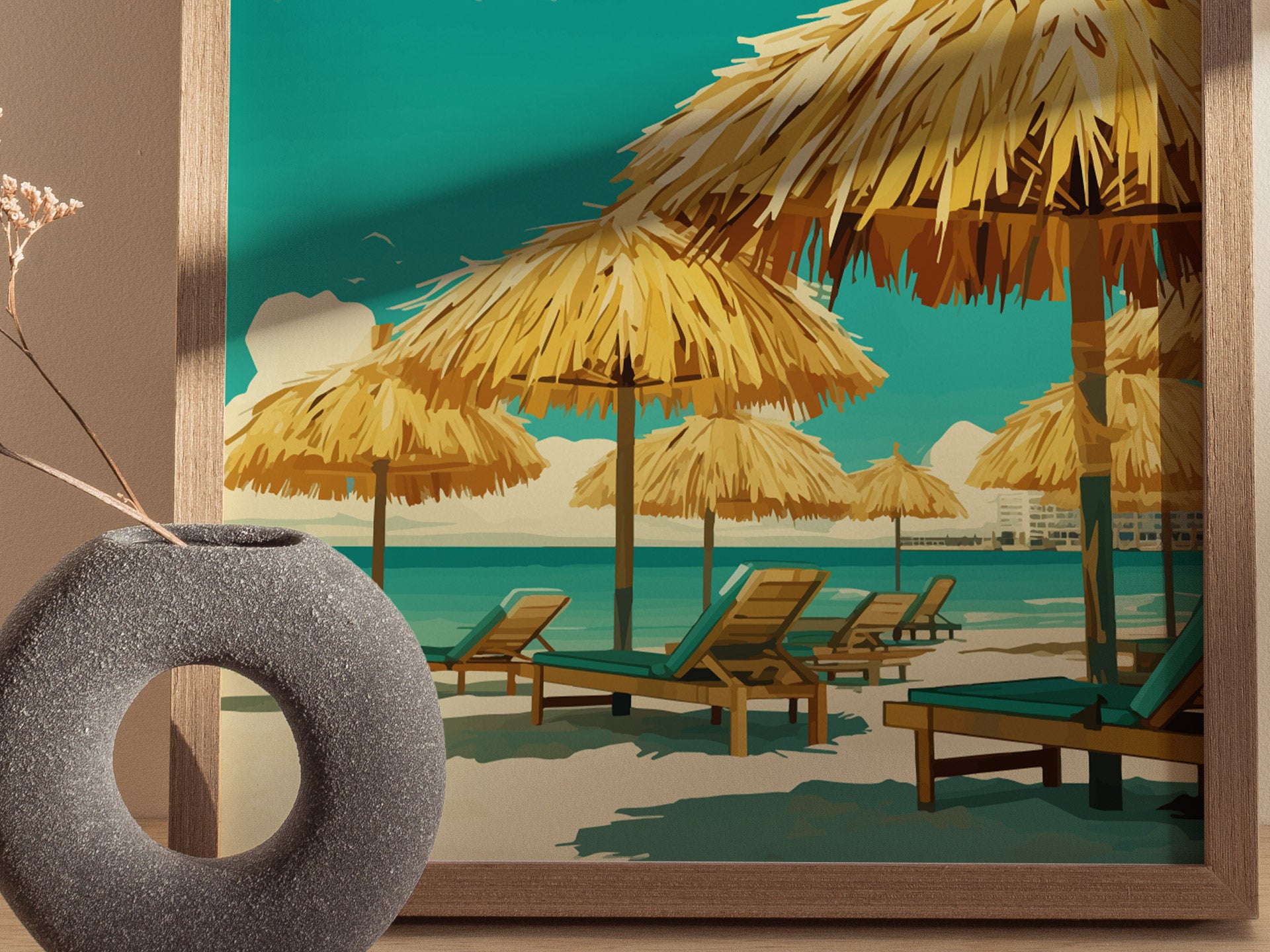 A framed poster depicts a tropical beach scene with straw umbrellas and lounge chairs under a clear blue sky. A decorative gray vase with dried flowers sits in the foreground.