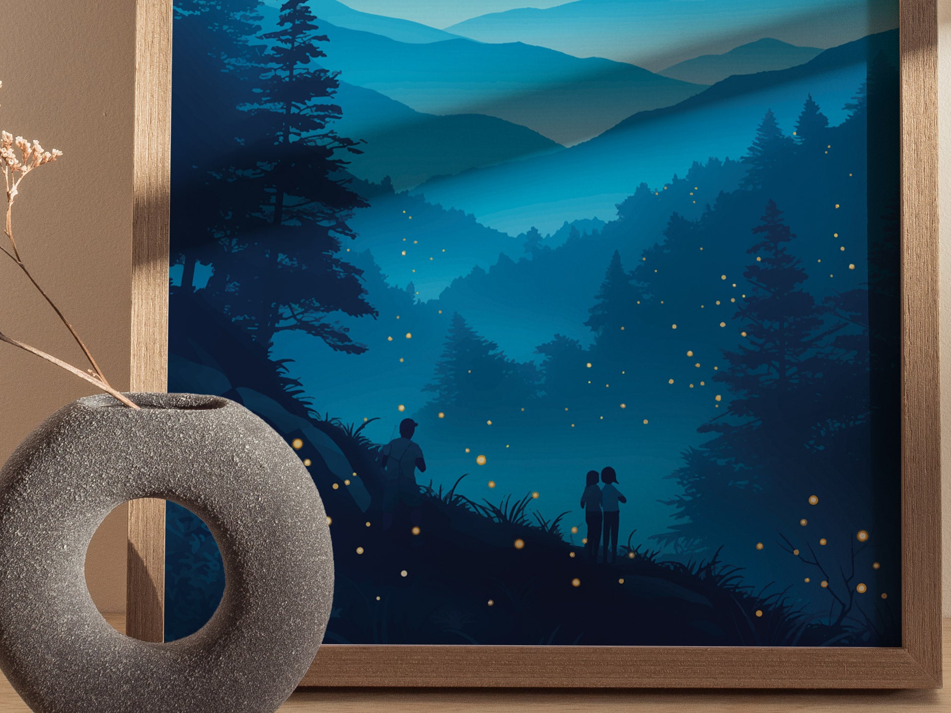 A framed poster depicting a serene night scene in the mountains, with silhouettes of trees and people observing numerous glowing fireflies. The foreground features a textured, circular gray vase with a dried plant.