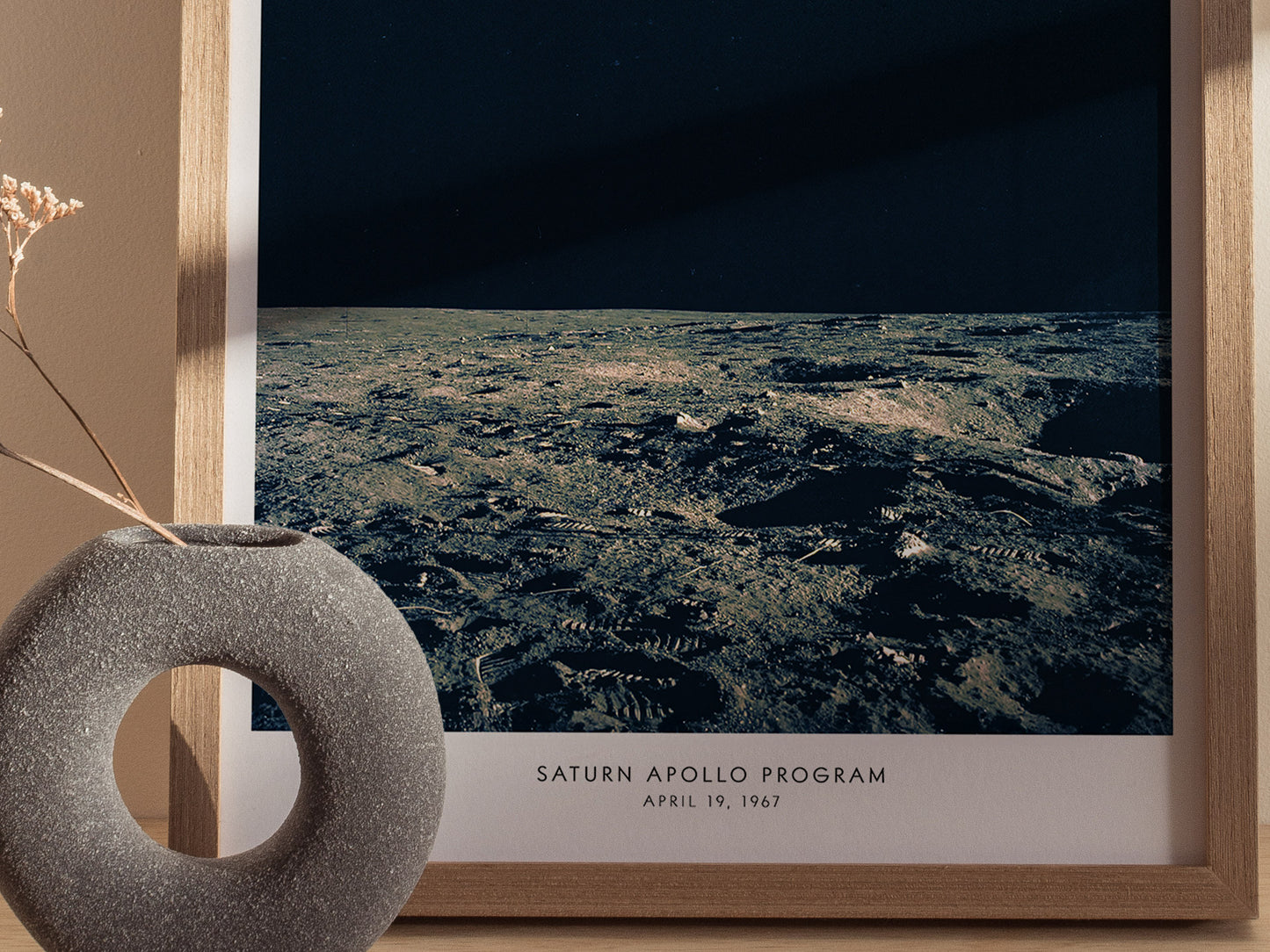 Framed photograph of the lunar surface with 'Saturn Apollo Program' text, next to a decorative vase.