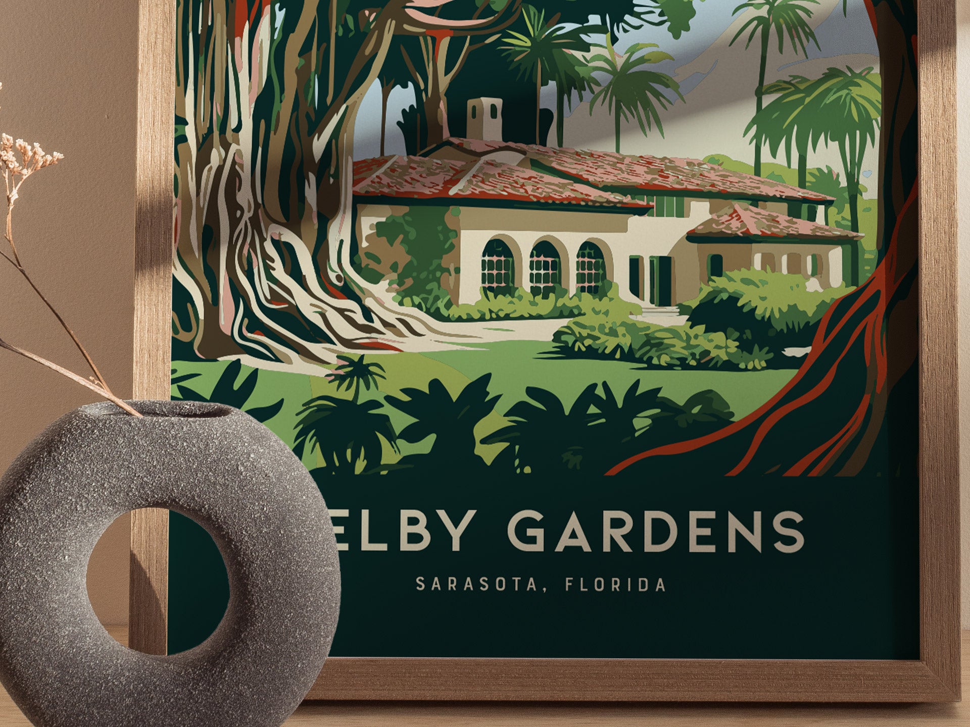 A framed poster features a lush botanical scene with a Mediterranean-style building surrounded by tropical plants, labeled Selby Gardens, Sarasota, Florida. A textured gray vase is in the foreground.