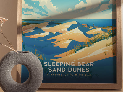 A framed poster of Sleeping Bear Sand Dunes depicts rolling sand dunes under a partly cloudy sky, with vibrant blue and golden tones.
