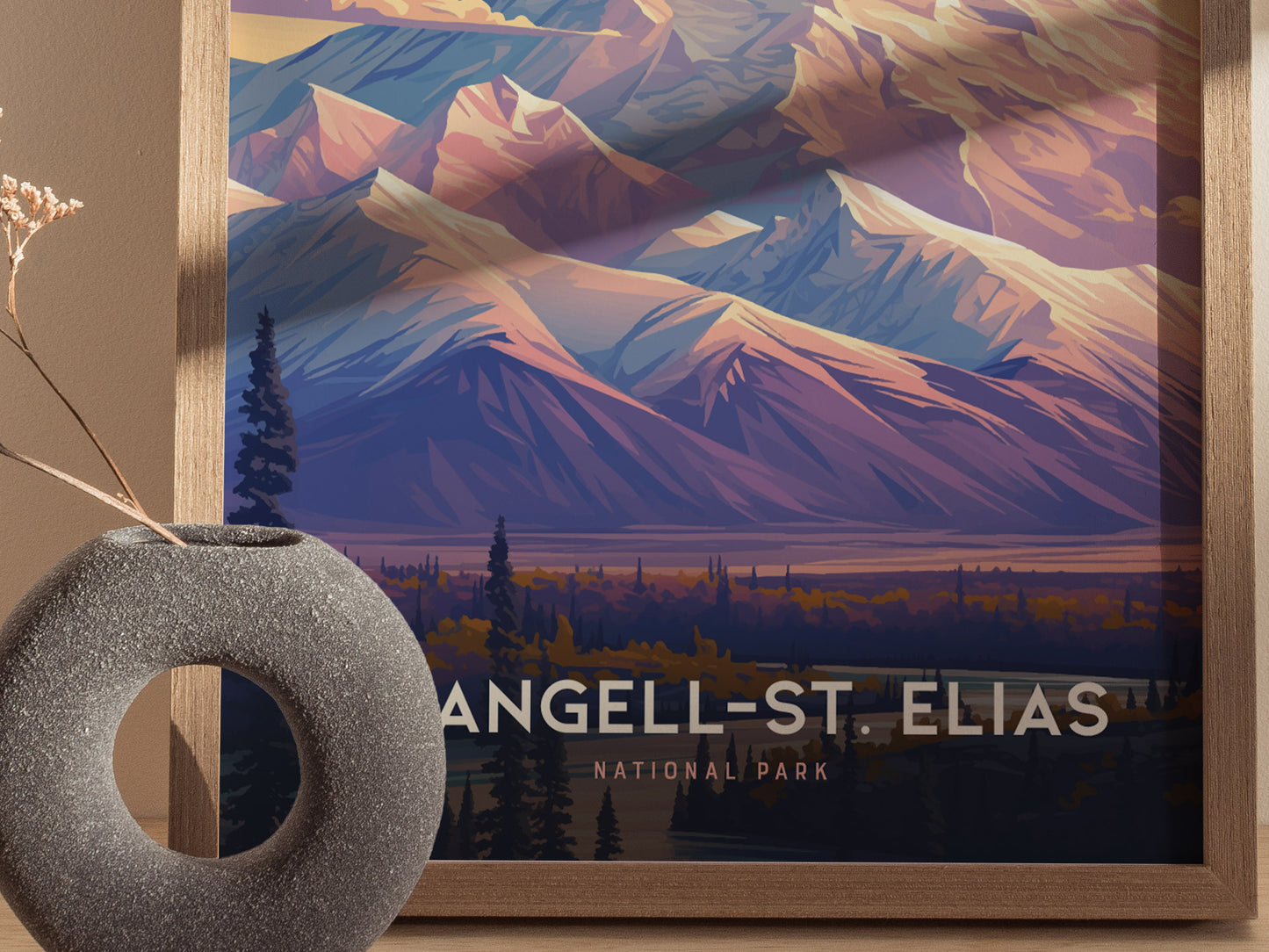 A framed poster of Wrangell-St. Elias National Park showcases vibrant, stylized mountain peaks and wilderness. A round, textured stone vase with dried flowers is in the foreground.