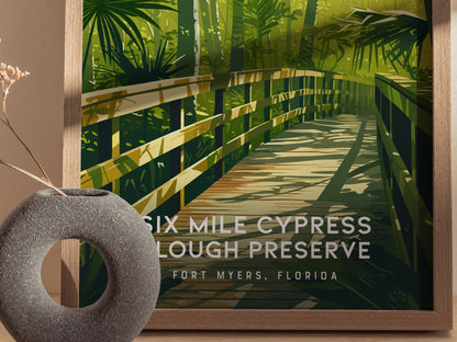 Framed artwork of a wooden boardwalk with greenery, labeled 'Six Mile Cypress Slough Preserve, Fort Myers, Florida', next to a decorative stone object.