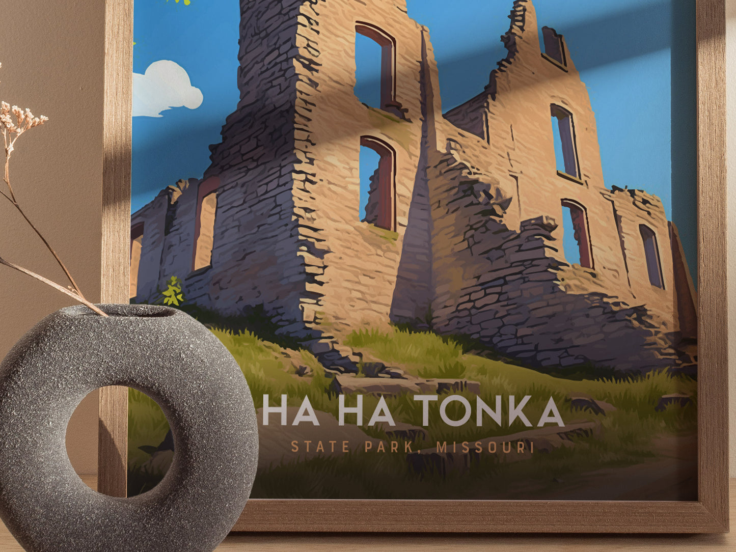 A framed poster of Ha Ha Tonka State Park in Missouri, featuring a stone ruin against a bright blue sky, is displayed next to a round, textured vase.