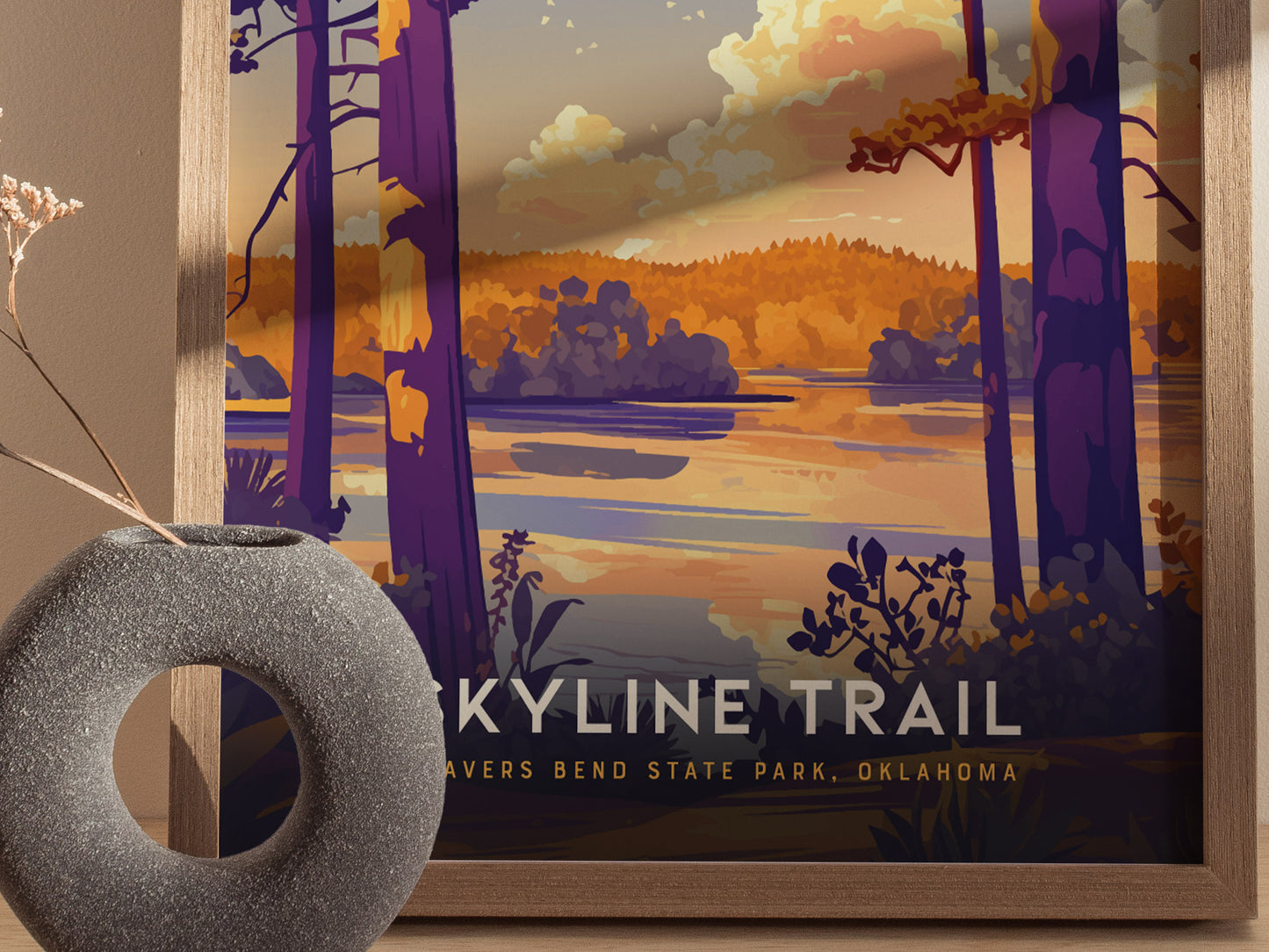 A framed poster depicts a scenic view of Beavers Bend State Park with vibrant trees and a tranquil lake at sunset. A textured, circular vase is positioned in the foreground.