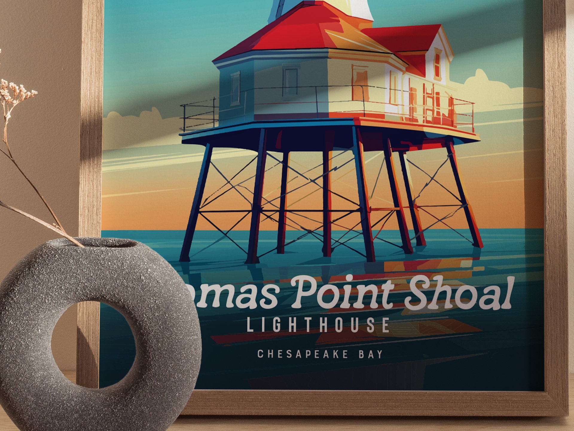 A colorful poster of Thomas Point Shoal Lighthouse on the Chesapeake Bay is framed on the wall, with a round gray vase in the foreground.