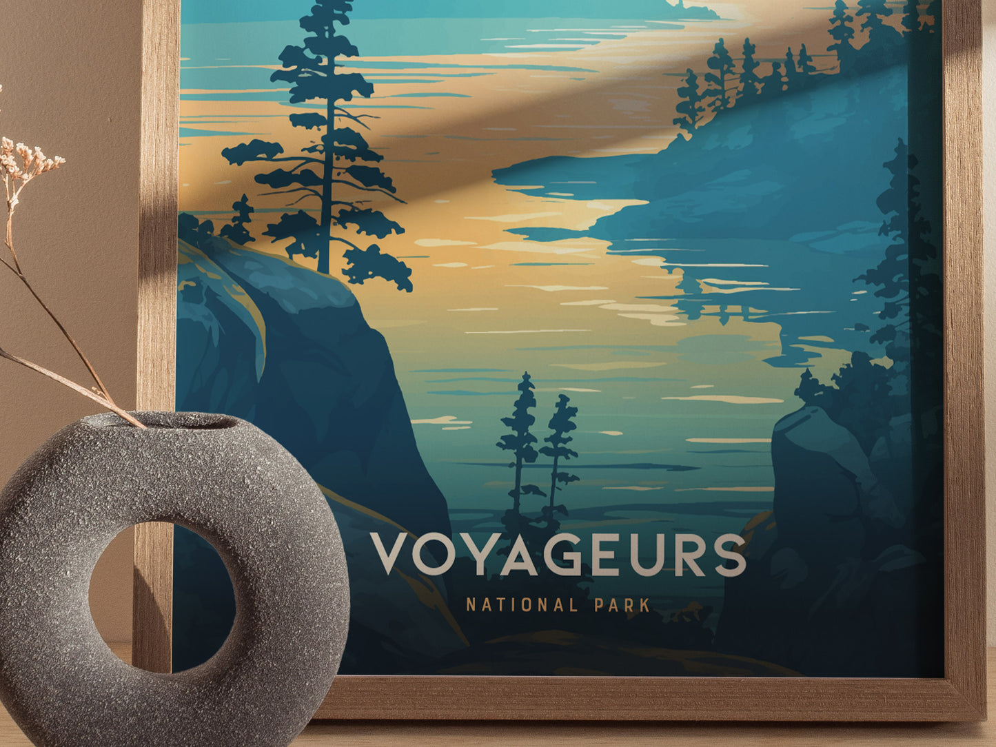Framed poster of Voyageurs National Park features stylized trees and water against a sunset sky. A round stone vase with dried flowers is placed nearby.