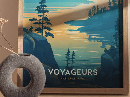 Framed poster of Voyageurs National Park features stylized trees and water against a sunset sky. A round stone vase with dried flowers is placed nearby.