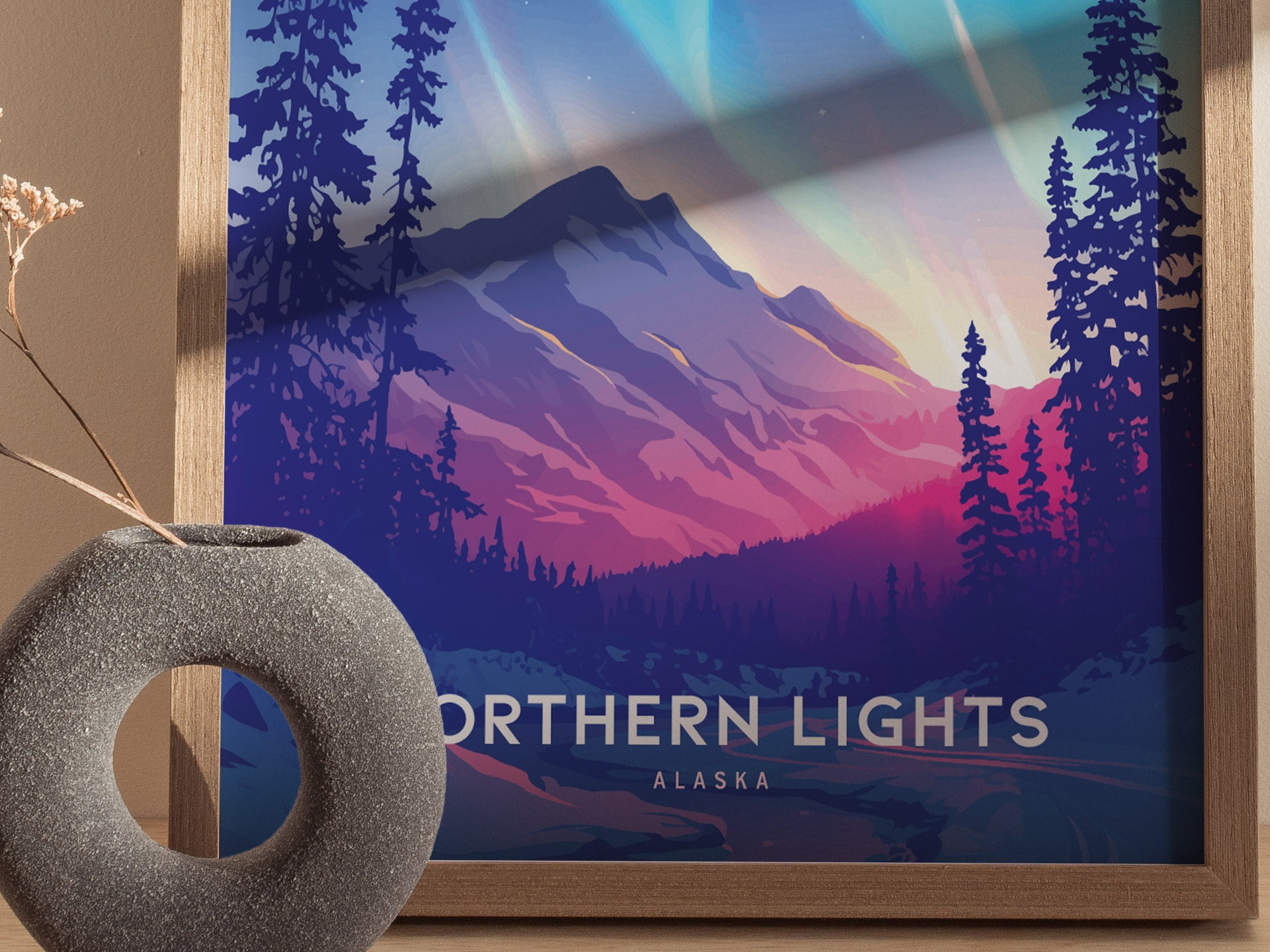 A framed poster titled Northern Lights Alaska features a colorful landscape with mountains, pine trees, and vibrant aurora. A textured gray vase sits nearby, complementing the artwork.