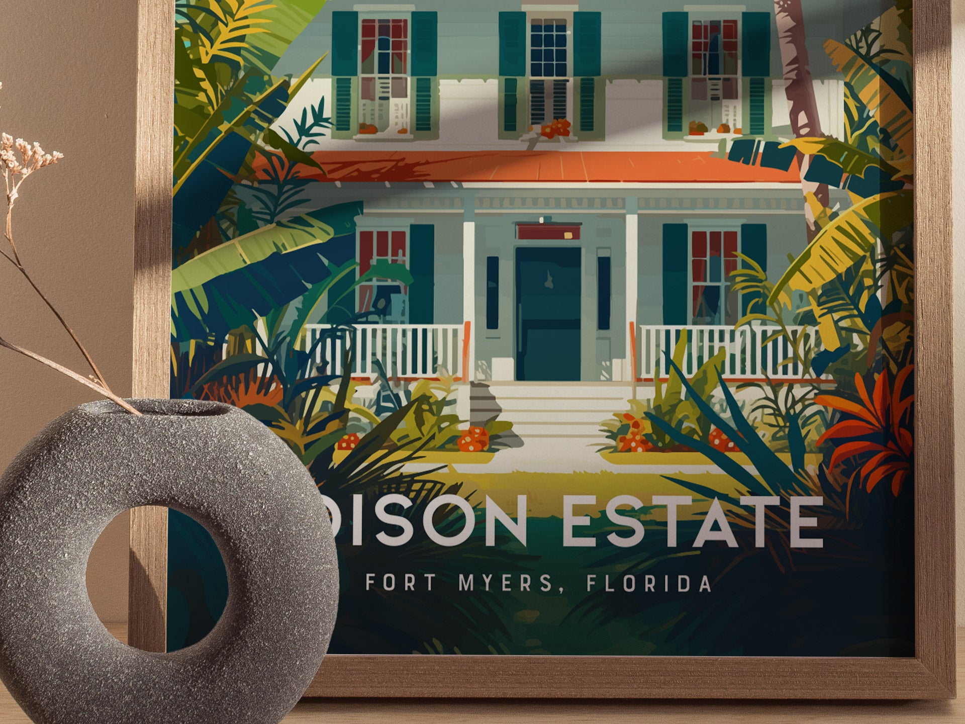 A framed poster of the Edison Estate in Fort Myers, Florida, features a colorful illustration of a house surrounded by lush greenery. A decorative vase is visible in the foreground.