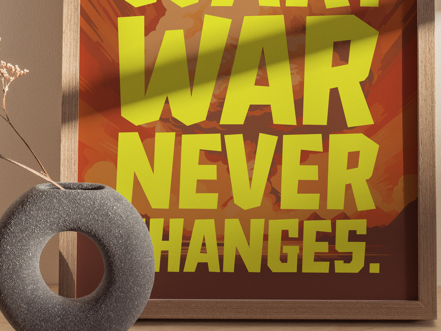A framed poster with bold yellow text reading WAR NEVER CHANGES against a background of muted reds and oranges. A textured, circular gray vase with dried flowers is in the.
