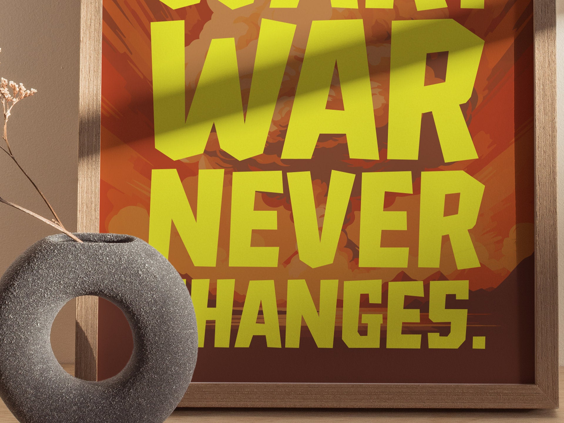 A framed poster with bold yellow text reading WAR NEVER CHANGES against a background of muted reds and oranges. A textured, circular gray vase with dried flowers is in the.