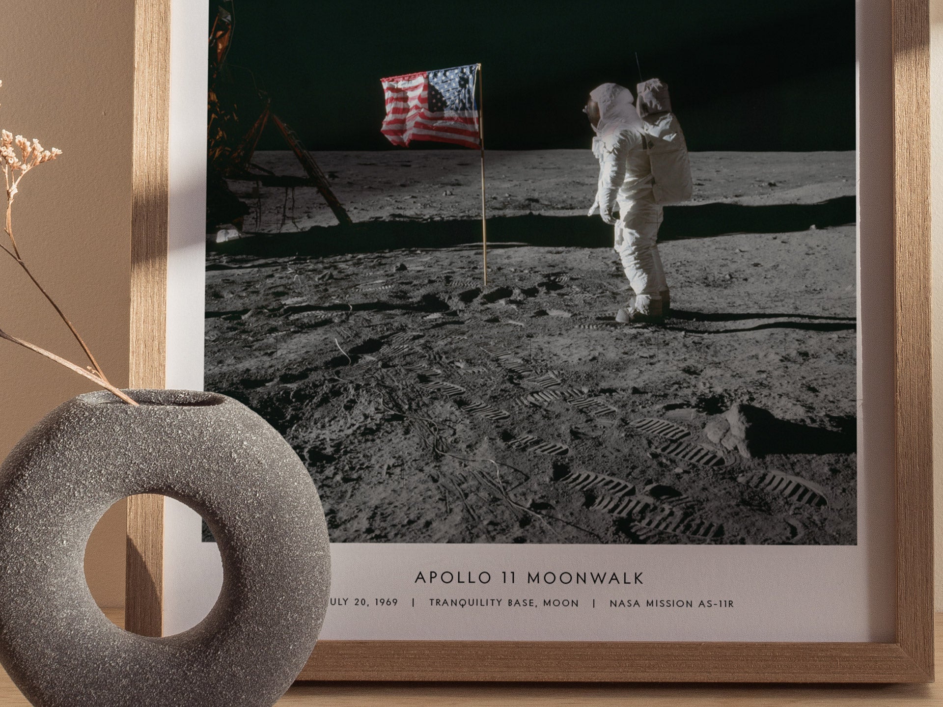 Framed photograph of an astronaut on the moon with a flag, leaning against a decorative wall piece.