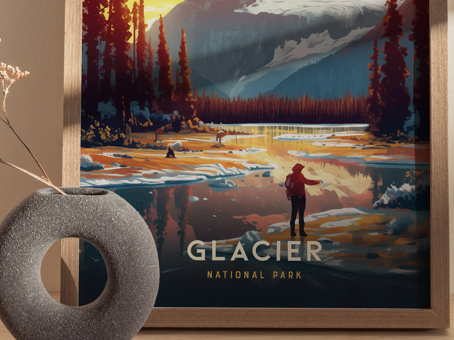 A framed poster depicting a scenic view of Glacier National Park with a person standing by a reflective lake surrounded by trees and mountains. A decorative vase sits nearby.