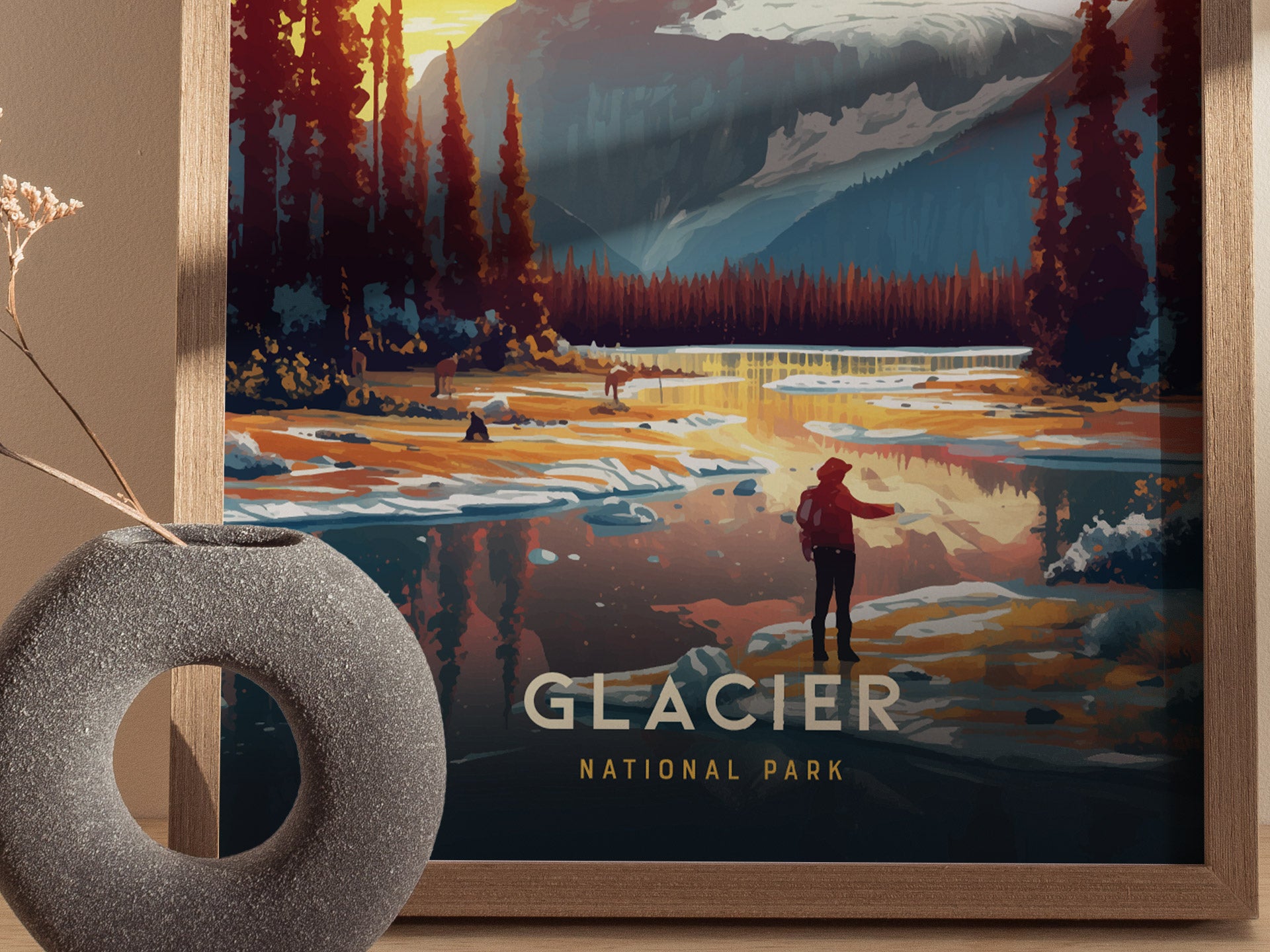 A framed poster depicting a scenic view of Glacier National Park with a person standing by a reflective lake surrounded by trees and mountains. A decorative vase sits nearby.